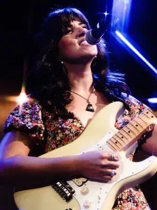 Woman singing and playing the guitar.